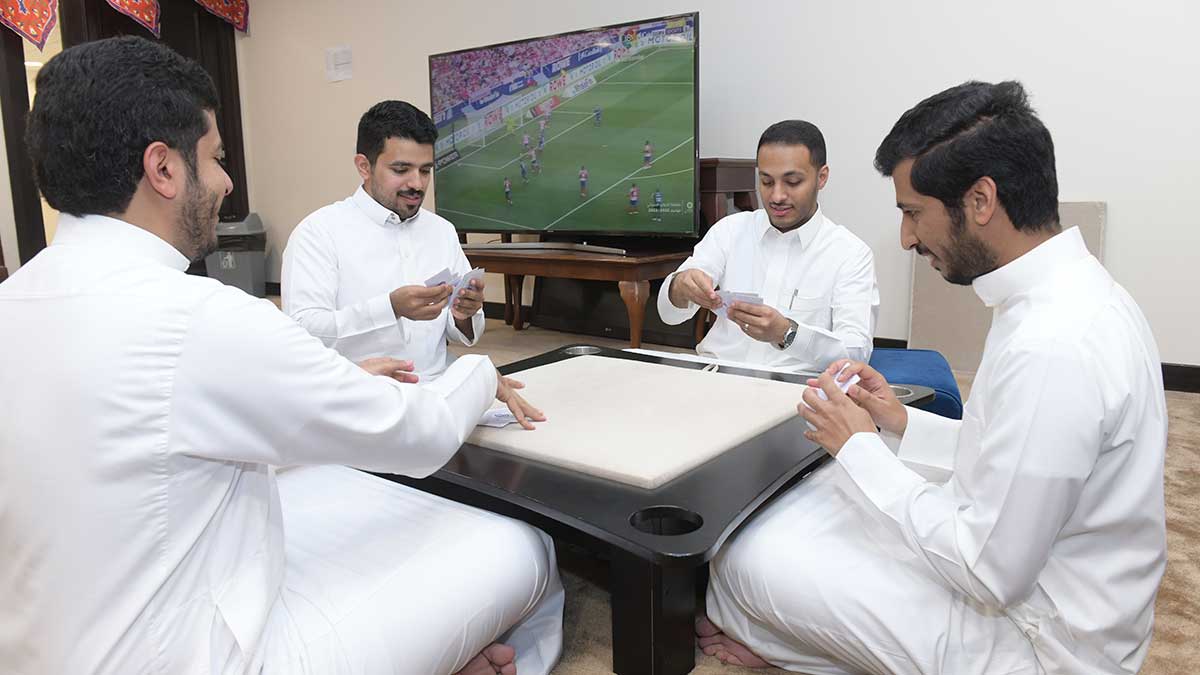 Aramco energy coordinator Abdullah Al-Zahrani playing cards with colleagues after work in Khurais